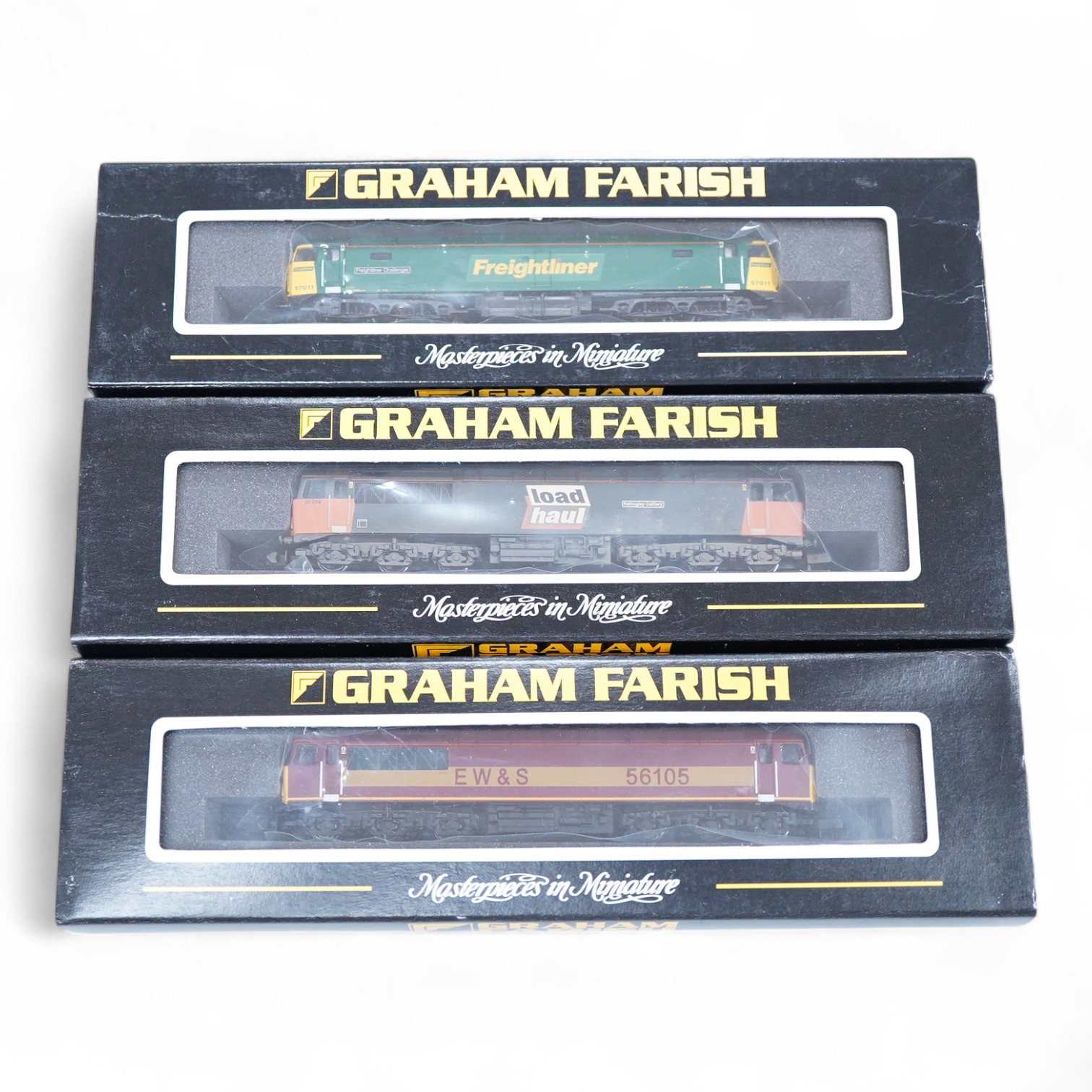 Three boxed Graham Farish N gauge railway diesel locomotives; an EWS class 56, 56105 (371300), a Load Haul class 56, Kellingley Colliery 56 074 (371301), and a Freightliner class 57, Freightliner Challenger 57011, (37122
